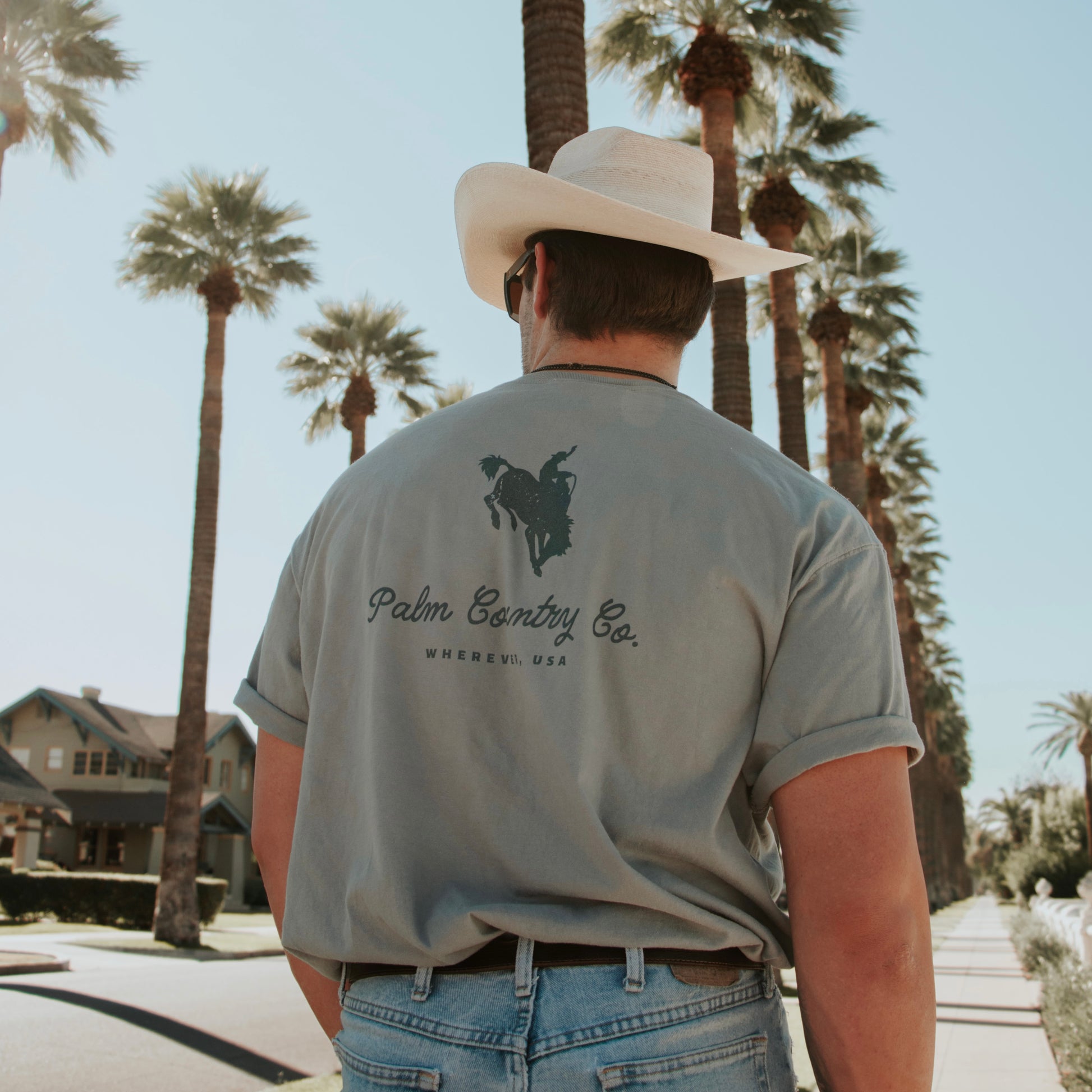 a man wearing a cowboy hat walking down a street